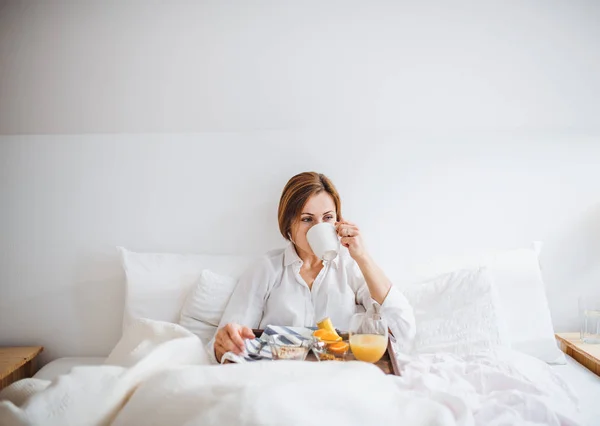 Una vista frontal de la mujer desayunando en la cama por la mañana . — Foto de Stock