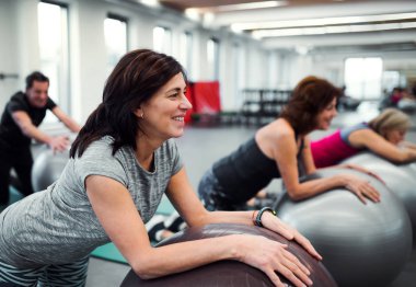 Neşeli kadın yaşlılar üzerinde egzersiz yaparak spor salonunda grup topu uygun.