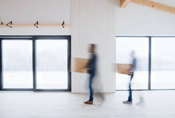 Two men walking with cardboard boxes when furnishing new house. Motion blur. — Stock Photo, Image