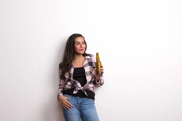 Jovem bela mulher feliz no estúdio, segurando garrafa de cerveja . — Fotografia de Stock