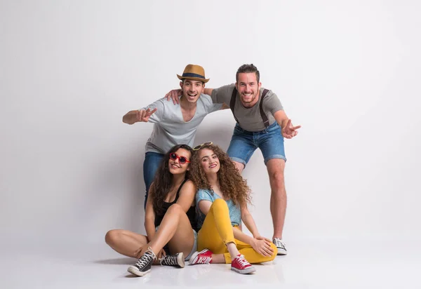 Retrato de jovem grupo alegre de amigos com chapéu em um estúdio, rindo . — Fotografia de Stock