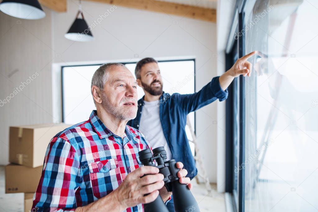 A senior man helping his son with furnishing new house, a new home concept.