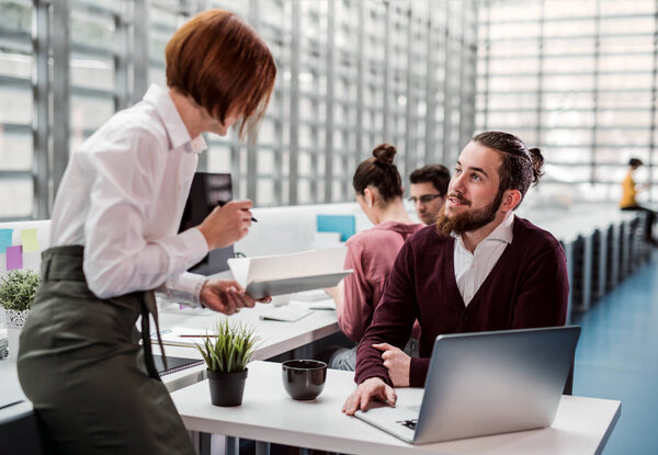 Group of young businesspeople working together in office, talking.