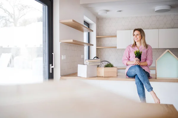 新しい家に移動、台所のカウンターに座っている若い女性. — ストック写真