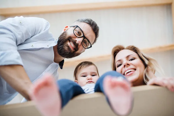 Una vista de bajo ángulo de la familia joven con una niña que se muda a un nuevo hogar . — Foto de Stock