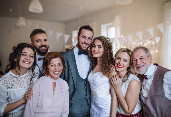 Une jeune mariée, marié et invités posant pour une photo sur une réception de mariage . — Photo