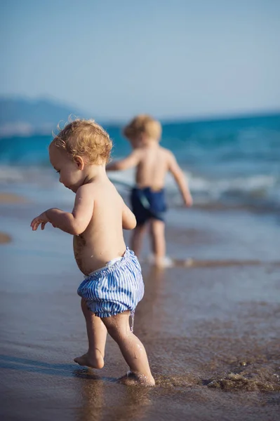 Dua anak kecil berjalan di pantai saat liburan musim panas . — Stok Foto