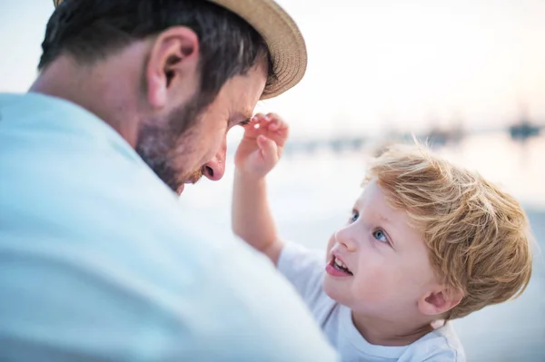 Ein Vater hält im Sommerurlaub einen kleinen Jungen am Strand. — Stockfoto
