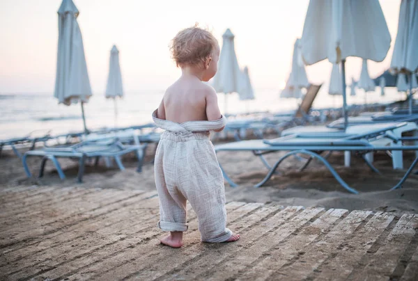 Pandangan belakang gadis balita kecil berjalan di pantai pada hari libur musim panas . — Stok Foto