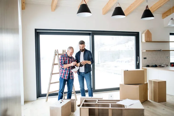 A mature man with his senior father assembling furniture, a new home concept. — Stock Photo, Image