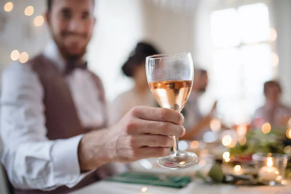 Een close-up van mannenhand binnenshuis in een kamer die is ingesteld voor een feest, een glas wijn te houden. — Stockfoto