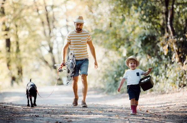 Un padre maduro con un pequeño hijo pequeño y un perro que va a pescar . —  Fotos de Stock