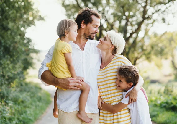 Ett porträtt av ung familj med små barn i solig sommar natur. — Stockfoto