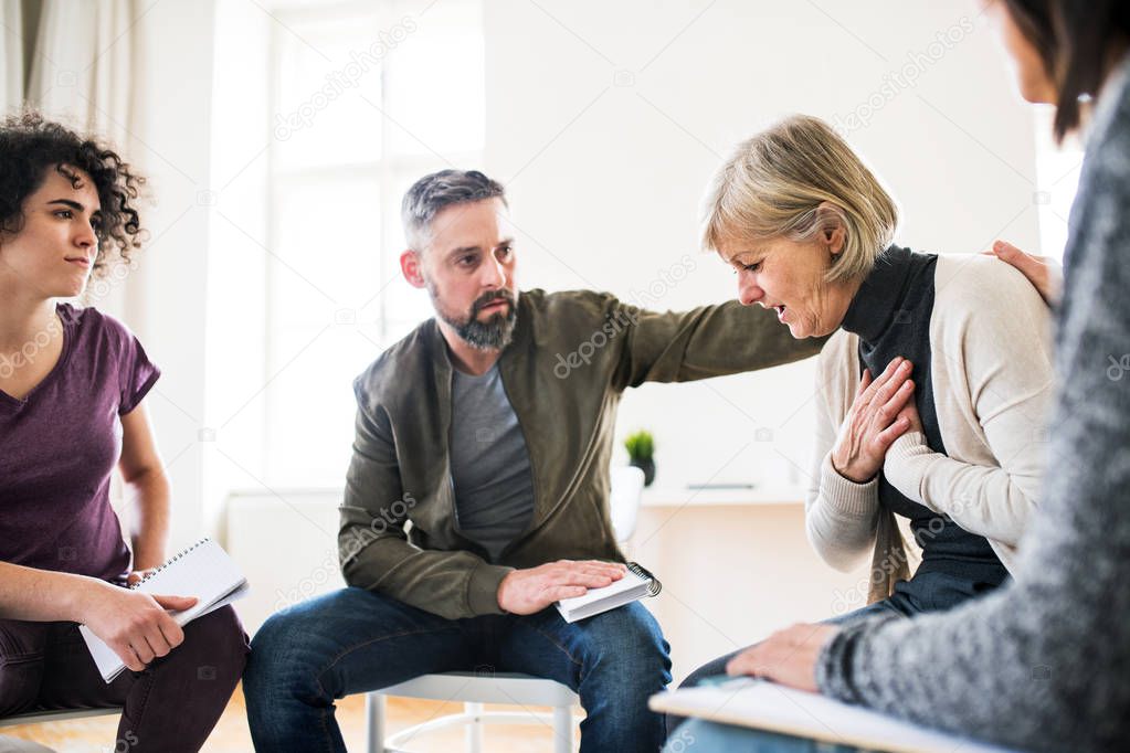 Men and women sitting in a circle during group therapy, supporting each other.