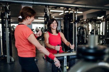 İki neşeli üst düzey kadın gücü egzersiz yaparken spor salonunda egzersiz.