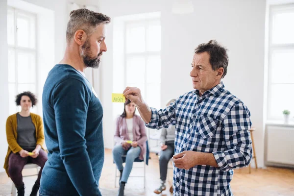 Counsellor putting an adhesive note with the word angry on client during group therapy. — Stock Photo, Image