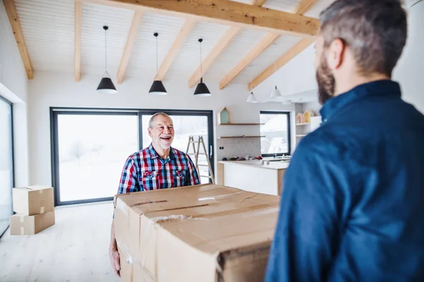 Un hombre mayor ayudando a su hijo a amueblar una casa nueva, un nuevo concepto de hogar . — Foto de Stock