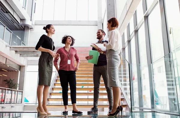 Group of young businesspeople standing near a staircase, talking. — Stock Photo, Image