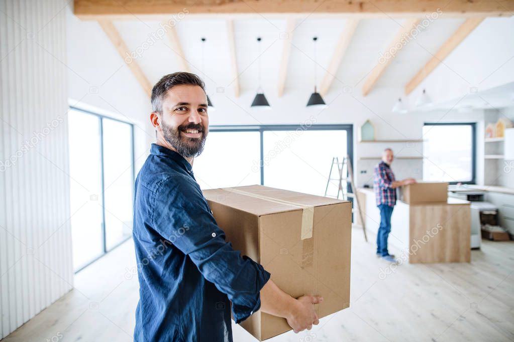 A mature man with his senior father furnishing new house, a new home concept.