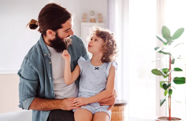Uma menina pequena com o jovem pai em casa, a falar. Espaço de cópia . — Fotografia de Stock