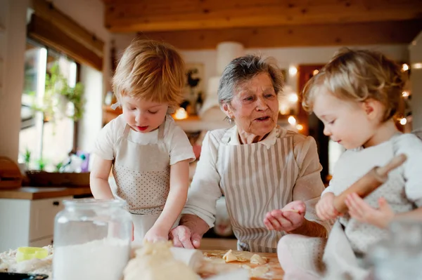 Grand-mère aînée avec des enfants en bas âge faisant des gâteaux à la maison . — Photo