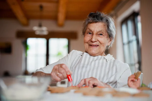 Bejaarde vrouw maken en decoreren van taarten in een keuken thuis. Kopiëren van ruimte. — Stockfoto