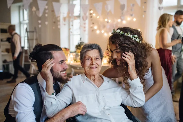 Una joven pareja con su abuela en una boda, posando para una fotografía . — Foto de Stock