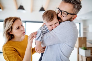 Ağlayan bir bebek kız evde kapalı ayakta ile genç bir aile.