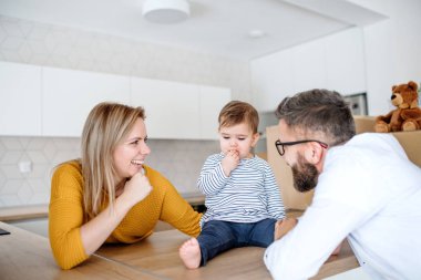 Yeni evinde hareketli bir yürümeye başlayan çocuk kızla genç aile portresi.