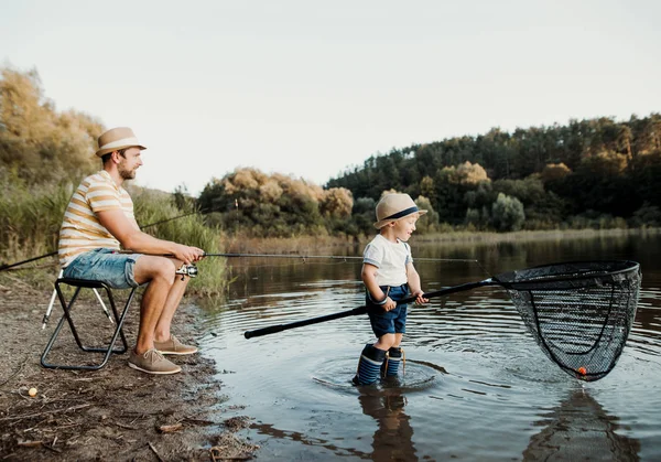 Зрілий батько з маленьким маленьким сином на відкритому повітрі рибалка біля озера . — стокове фото