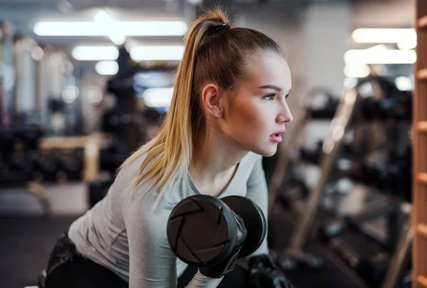 Genç kız ya da bir spor salonunda egzersiz yapıyor kadın dumbbells ile. — Stok fotoğraf