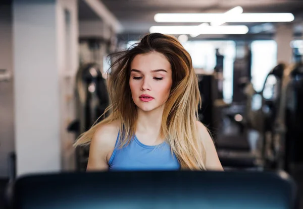 A portrait of young girl or woman doing cardio workout in a gym. — Stock Photo, Image