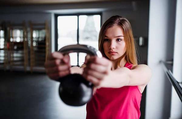 Genç kız ya da bir spor salonunda bir kettlebell ile egzersiz yaparak kadın portresi. — Stok fotoğraf