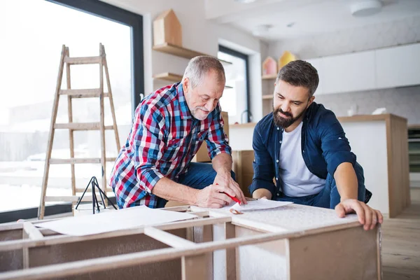 Un uomo maturo con il padre anziano che assembla mobili, un nuovo concetto di casa . — Foto Stock