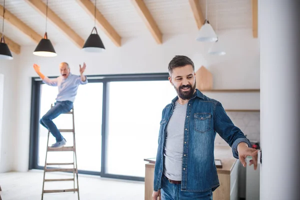 Un hombre mayor ayudando a su hijo a amueblar una casa nueva, un nuevo concepto de hogar . — Foto de Stock