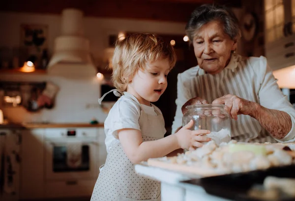 집에서 케이크를 만드는 작은 유아 소년과 함께 수석 할머니. — 스톡 사진
