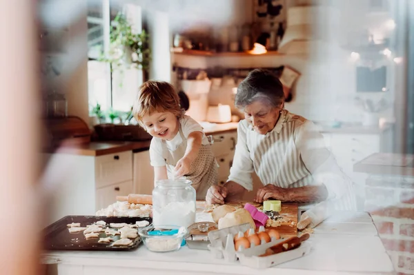 Senior grandmother with small toddler boy making cakes at home. — Stock Photo, Image