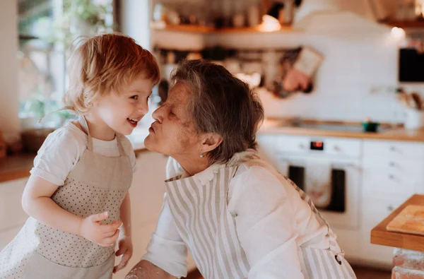 Senior grandmother with small toddler boy making cakes at home, kissing. — Stock Photo, Image