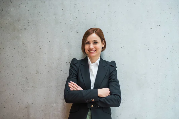 Porträt einer jungen Geschäftsfrau, die im Büro steht und in die Kamera blickt. — Stockfoto