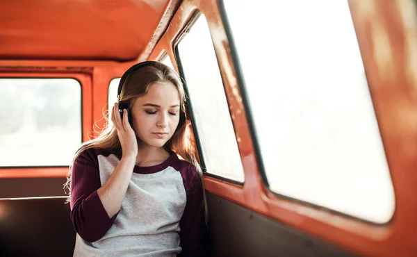 Des amis en voyage à travers la campagne, une fille avec des écouteurs écoutant de la musique . — Photo