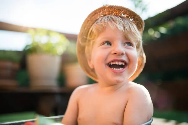 Small boy with a hat outdoors in garden in summer, laughing. Copy space. — Stock Photo, Image