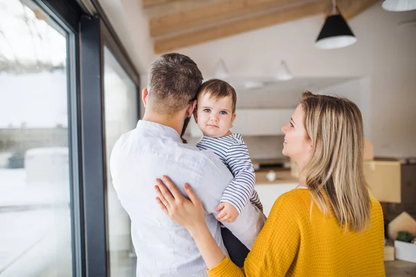 Yeni evinde hareketli bir yürümeye başlayan çocuk kızla genç aile portresi. — Stok fotoğraf