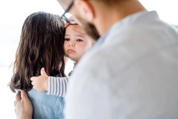 A young family with a crying toddler girl standing indoors at home. — Stock Photo, Image