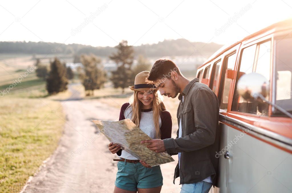 A young couple on a roadtrip through countryside, looking at a map.