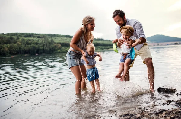 Een jong gezin met twee kinderen van peuter buitenshuis door de rivier in de zomer. — Stockfoto