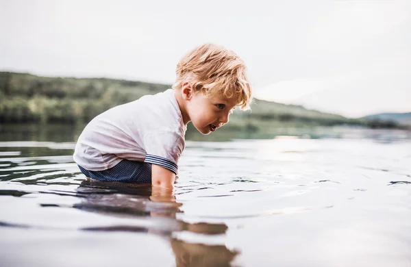 En liten toddler pojke spela utomhus vid floden i sommar. — Stockfoto