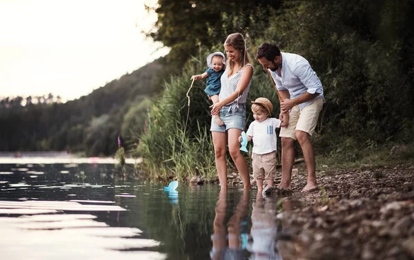 Una giovane famiglia con due bambini piccoli all'aperto vicino al fiume in estate . — Foto Stock