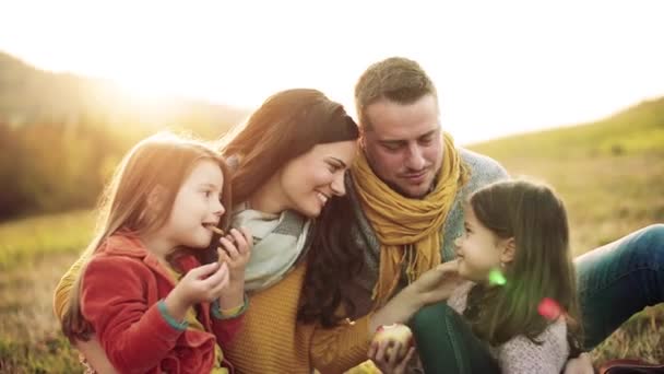 A young family with two small children sitting on grass in autumn nature. — Stock Video