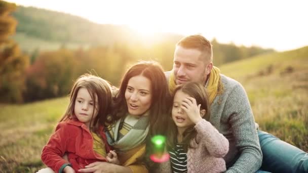 Una giovane famiglia con due bambini piccoli seduti sull'erba in autunno natura . — Video Stock