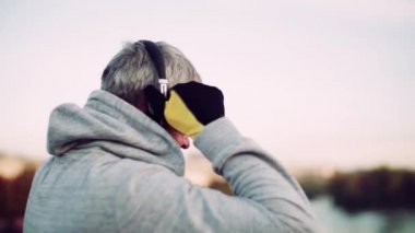 Olgun Erkek atlet açık havada şehirde kulaklıklar koyarak.